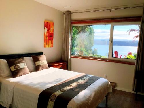 sypialnia z łóżkiem i dużym oknem w obiekcie Ocean's Edge Suite w mieście Campbell River
