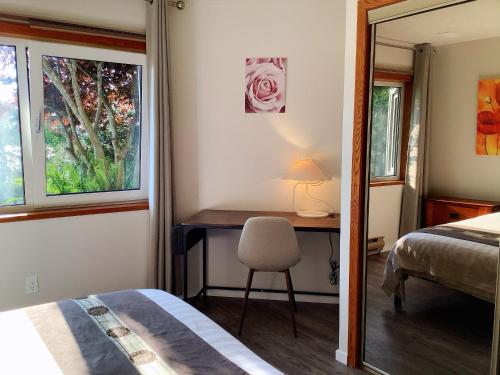 a bedroom with a desk and a bed and a window at Ocean's Edge Suite in Campbell River