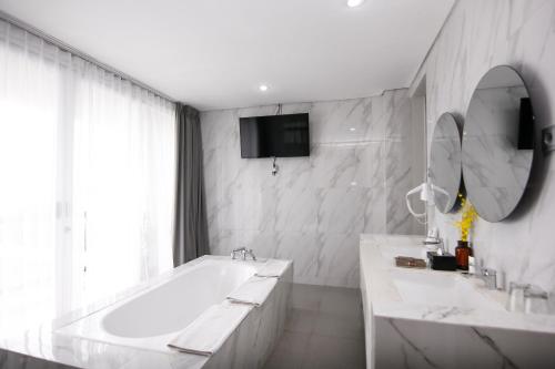 a bathroom with a tub and a sink and a mirror at Raja Hotel Kuta Mandalika Resort & Convention in Kuta Lombok