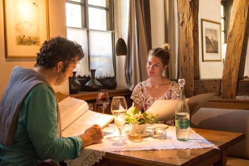a man and a woman sitting at a table with wine glasses at Landgasthof Zum Weissen Schwanen in Braubach