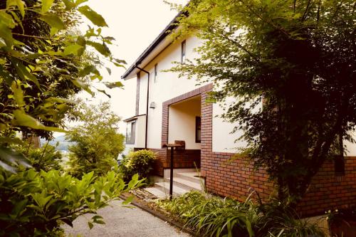 uma pequena casa branca com uma parede de tijolos em 森の香 em Matsue