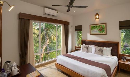 a bedroom with a bed and a large window at Jeevess Ayurveda Resort in Wayanad
