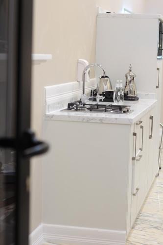 a white kitchen with a sink and a counter at الأجنحة الرخامية فندقية in Buraydah