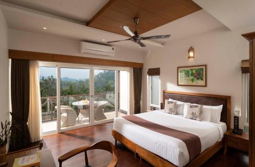 a bedroom with a large bed and a balcony at Jeevess Ayurveda Resort in Wayanad