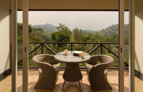 a table and chairs on a balcony with a view at Jeevess Retreat Wayanad in Wayanad