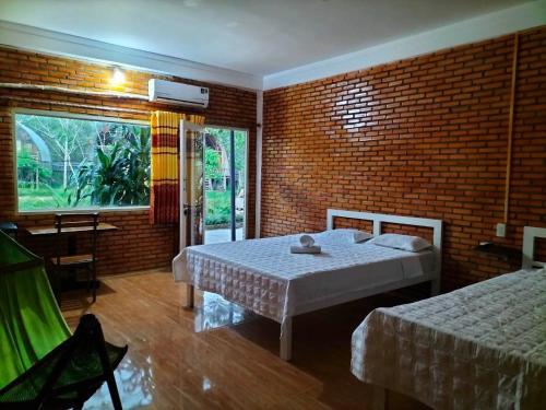 a bedroom with two beds and a brick wall at FOREST BREATH ECO-LODGE in Tân Phú