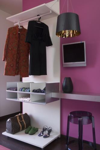 a room with a pink wall with shelves and a tv at Eh13 Luxury Accommodation in Catania