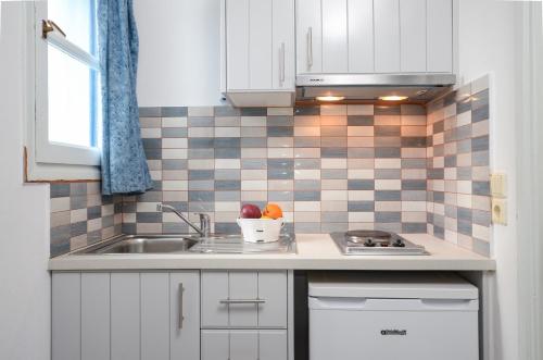 a kitchen with white cabinets and a sink at Galazia Studios in Naxos Chora