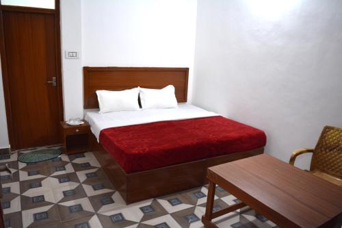 a bedroom with a bed with a red blanket and a bench at Rani Homestay Khajuraho in Khajurāho