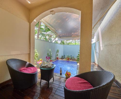a patio with two chairs and a swimming pool at Royal Orchid Beach Resort & Spa, Utorda Beach Goa in Utorda