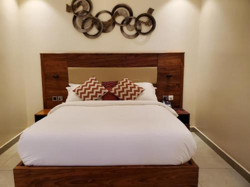 a bedroom with a large bed with white sheets at Millennium Terrace Hotel in Kampala