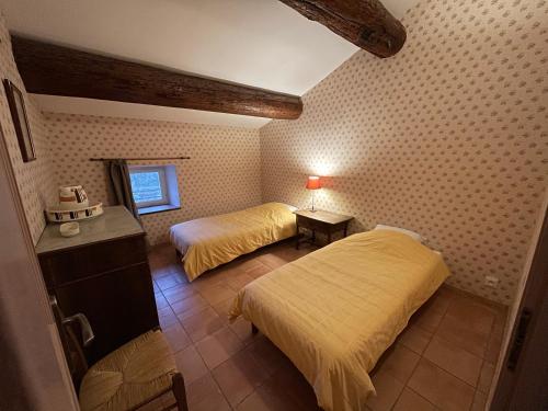 une chambre avec deux lits et une table et une fenêtre dans l'établissement Ancien Mas viticole à 10 min de Narbonne, à Bizanet