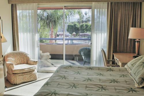 a bedroom with a bed and a chair and a balcony at Marquis Villas Resort in Palm Springs