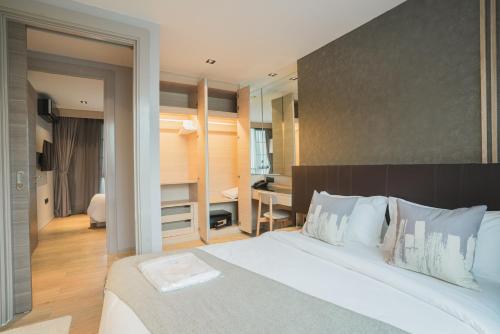 um quarto com uma grande cama branca e uma secretária em VOQUE Hotel & Serviced Residence Sukhumvit 51 - SHA Plus em Bangkok