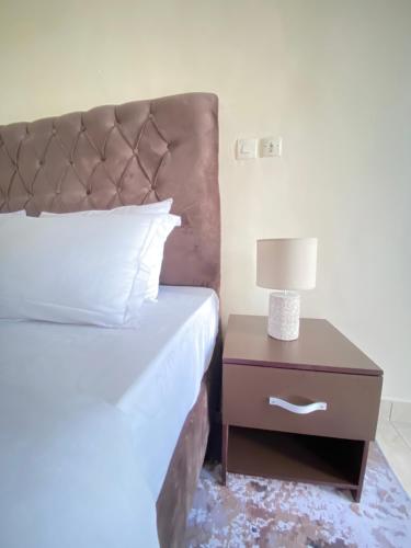 a bedroom with a bed and a nightstand with a lamp at Armelle Sweet Home in Douala