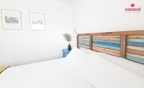 1 dormitorio con cama blanca y cabecero de madera en Apartamento Caracol - CORDOBA en Córdoba