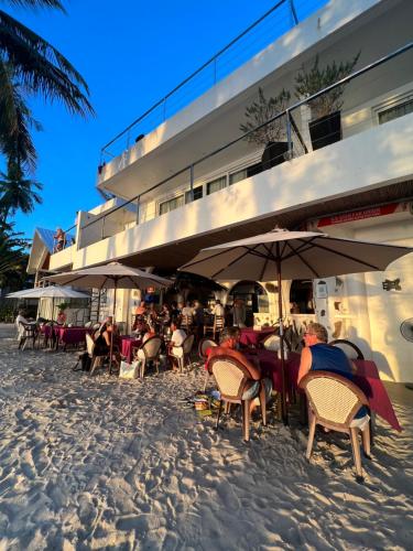 a group of people sitting in chairs under umbrellas on the beach at Sundown Resort in Boracay