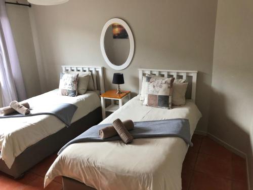 two beds in a room with a mirror at Mitford Views in Morganʼs Bay