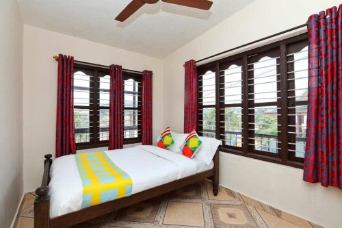 a bedroom with a bed and two windows at AAdya. Homestay in Madikeri