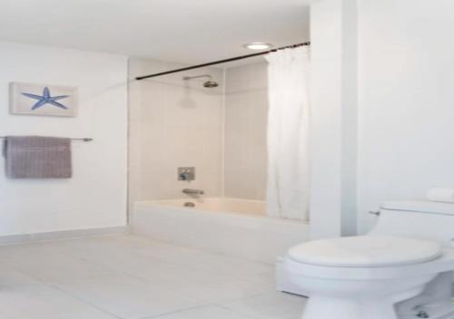 a white bathroom with a toilet and a bath tub at Two Bedroom Apartment with Pool At Midblock Miami in Miami