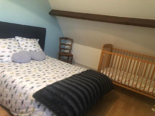 a bedroom with a bed and a crib and a chair at gite des 3 pleureuses in Saint-Riquier