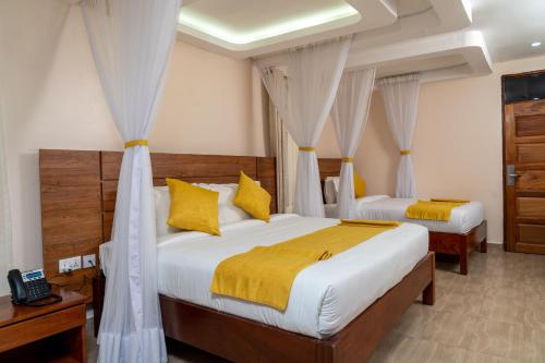 1 dormitorio con 2 camas con almohadas amarillas en Burch's Resort Naivasha, en Naivasha