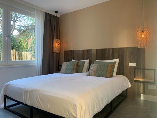um quarto com uma grande cama branca e 2 almofadas em Olive Beach, luxury beachhouse 150 m from the beach em Noordwijk aan Zee