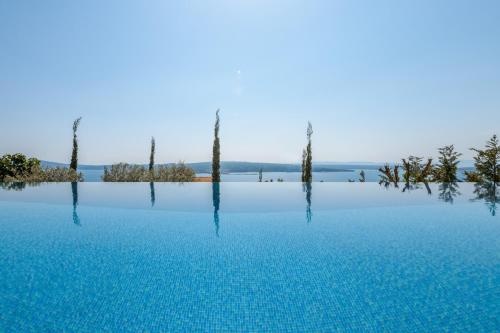 basen z błękitną wodą z drzewami w tle w obiekcie Villa Panorama w Crikvenicy