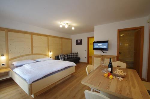 a bedroom with a bed and a table and a television at Villa Hubertus in Ortisei