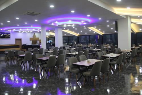 Arhavi的住宿－Arhavi Resort Otel，一间配备有桌椅和紫色照明的用餐室