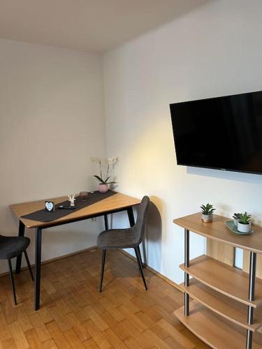 een tafel met een stoel en een televisie aan een muur bij Einzimmerwohnung im Grünen/Innsbruck/2 PAX in Innsbruck