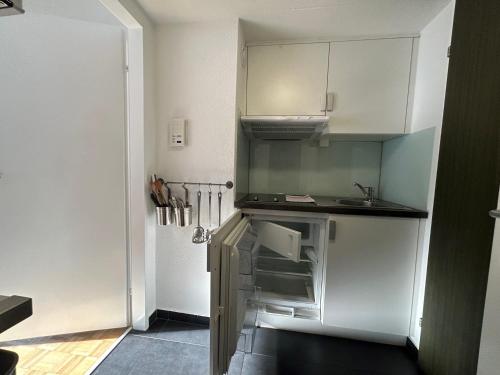 una pequeña cocina con armarios blancos y fregadero en Guesthouse Elisa 6 en Zúrich