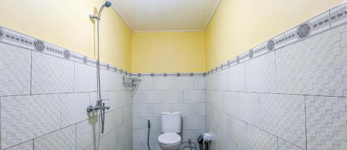a bathroom with a toilet and a yellow wall at The Salang Guest House in Nusa Penida