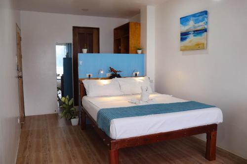 a bedroom with a bed with a blue headboard at The Beach House in El Nido