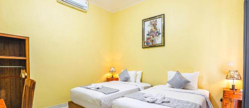 two beds in a room with yellow walls at The Salang Guest House in Nusa Penida