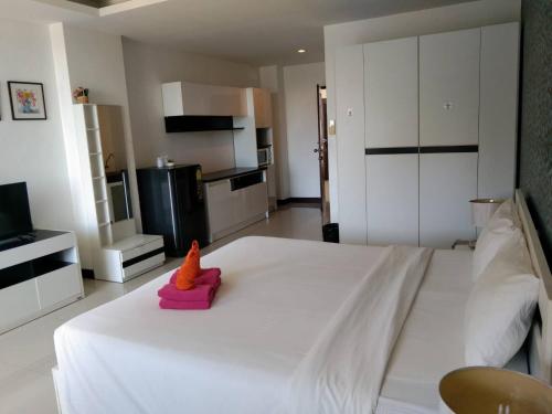 Un dormitorio con una gran cama blanca con un juguete de dinosaurio. en Grand Residence Jomtien en Jomtien Beach