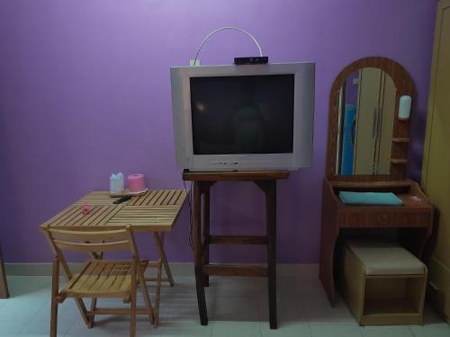 a living room with a tv and a table with a chair at Baan Nakarin Guest House บ้านนครินทร์ in Patong Beach