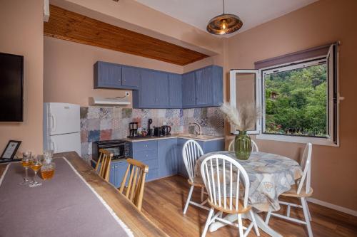 una cocina con armarios azules y una mesa con sillas en Tzoumerka Secret House, en Vourgareli