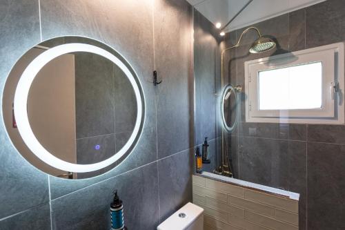 baño con espejo redondo y aseo en Tzoumerka Secret House, en Vourgareli