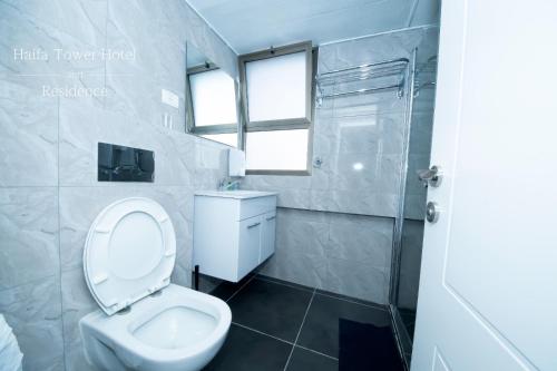 uma casa de banho com um WC, um lavatório e um chuveiro em Haifa Tower Hotel - מלון מגדל חיפה em Haifa