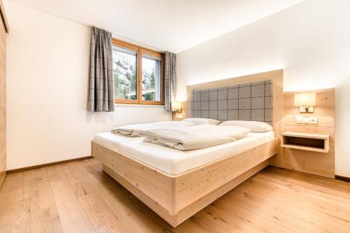 ein Schlafzimmer mit einem großen Bett und einem Fenster in der Unterkunft Appartements im Kirchberg by A-Appartments in Fontanella