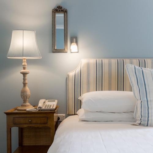 a bed with a lamp and a phone on a table at The Beach House At Bayside in Albany