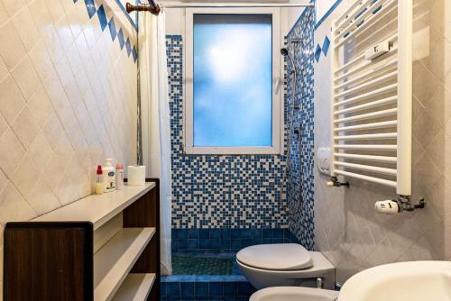 een badkamer met een toilet, een wastafel en een raam bij Via Mocenigo in Venetië-Lido