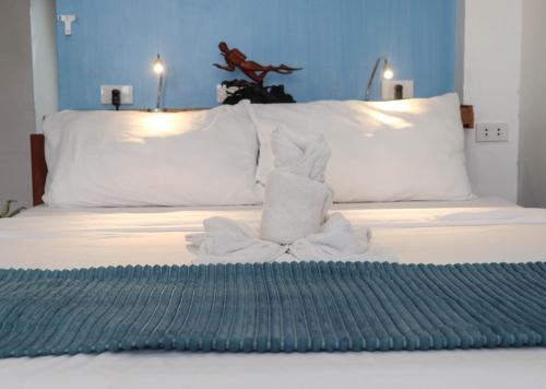 a bed with a pile of towels on it at The Beach House in El Nido