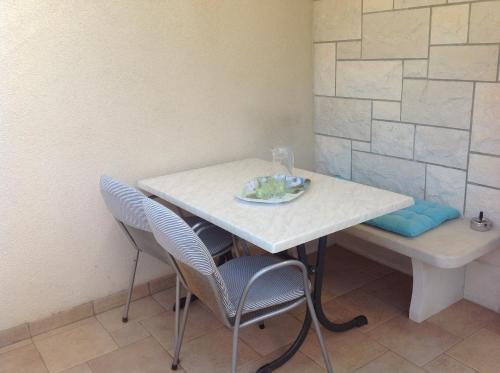 a white table and chairs with a plate on it at Apartmani ROBERTA in Bol