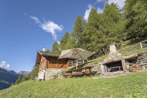 a stone building with an umbrella on a hill at Chalet indipendente Mas Tarlenta nel Parco Nazionale dello Stelvio in Peio