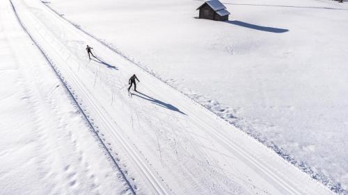 two people are walking through the snow at Hotel Bergland in Sillian