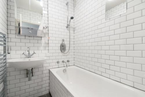 a white bathroom with a tub and a sink at Platform 9 3/4 by condokeeper in London