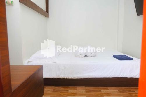 a bedroom with a bed with white sheets at Guest House Bibong Makassar Mitra RedDoorz in Makassar