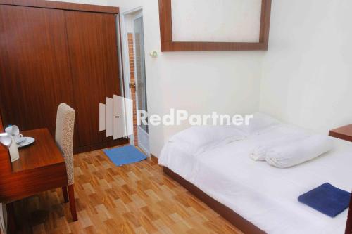 a bedroom with a bed and a table and a desk at Guest House Bibong Makassar Mitra RedDoorz in Makassar